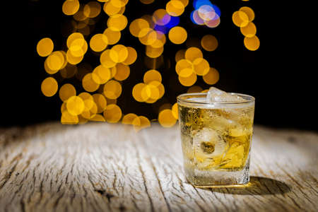 A liquor glass or beer mug on a wooden table in a tavern Yellow bokeh background Soft focus conveys the feeling of being lonely.の写真素材