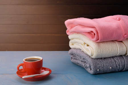 Gray knit sweater Pink and white with a coffee cup placed on a blue wooden table And a faint sunlight shone inの写真素材