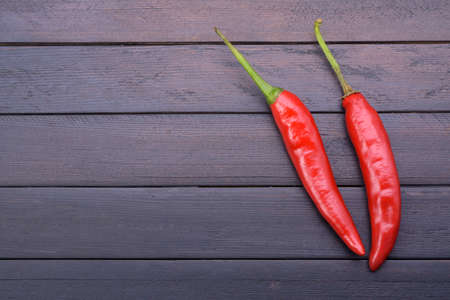 Red peppers placed on a dark vintage wooden table top view
