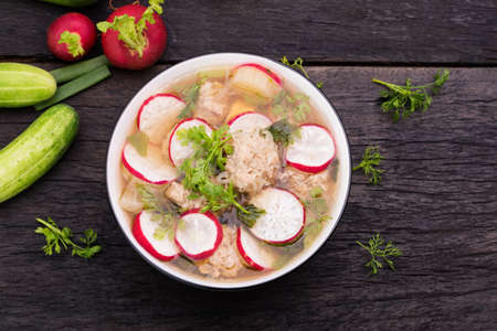 Hot soup with radish, cucumber, and parsley on a wooden tableの写真素材