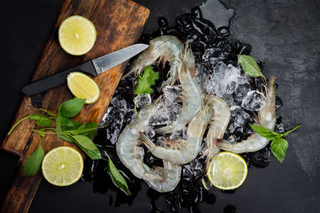 Fresh shrimp with lemon basil leaves on ice Raw shrimp from the sea placed on a black table, seafood menu, top view.の写真素材