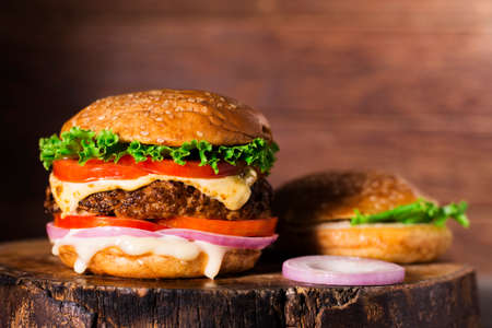 Close-up of delicious homemade burgers on a wooden table on a dark background beef hamburger freshly cooked deliciousの写真素材