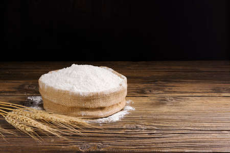 Organic Natural Whole Grain Flour in Sacks and wheat seeds Ears of wheat on an old wooden floor