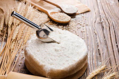 Organic Natural Whole Grain Flour in Sacks and wheat seeds Ears of wheat on an old wooden floorの写真素材