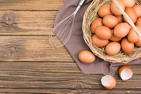 Chicken eggs in a basket Farm fresh organic eggs laid on a rustic wooden table, top view.