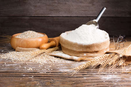 Organic Natural Whole Grain Flour in Sacks and wheat seeds Ears of wheat on an old wooden floorの写真素材