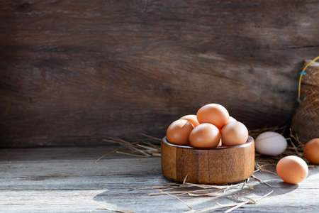 Chicken eggs are laid on the ground and put in a basket on a wooden table on, a rural farm