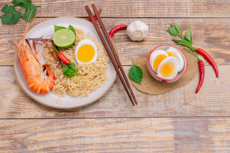 Tom Yum Goong Instant Noodle Ramen - Asian Style Thai and Chinese are spicy. Placed on a wooden table, seafood shrimp, lime, red chili, garlic, galangal, lemongrass, kaffir lime stand originalの写真素材