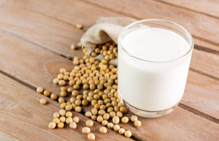 Soy milk in a glass with soybeans on a wooden table organic drink high protein healthy breakfast agricultural produce vegetarian - top viewの写真素材