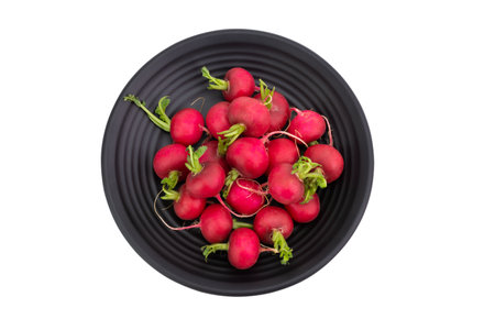 Red or purple radishes are placed on a black plate. Organic salad, healthy natural food ingredients. isolated on white background, top view - clipping pathの写真素材