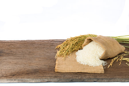 Organic white rice or jasmine rice in a sack placed on a wooden floor on a white backgroundの写真素材