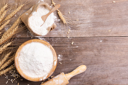 wheat flour in a wooden bowl There are ears of wheat on the table. Old wooden background - top viewの写真素材