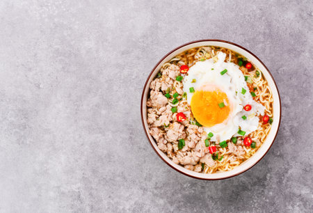 Instant noodles or ramen with minced pork and boiled egg in white bowl on the table with copy space - top viewの写真素材