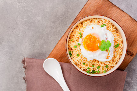 Instant noodles or ramen with minced pork and boiled egg in white bowl on the table with copy space - top viewの写真素材