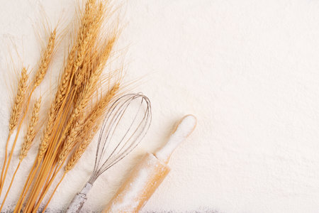Flour and ears of wheat, barley, cooking, bread, and cookies are arranged on the table in a rustic kitchen, top view.の写真素材