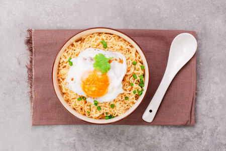 Instant noodles or ramen with minced pork and boiled egg in white bowl on the table with copy space - top viewの写真素材