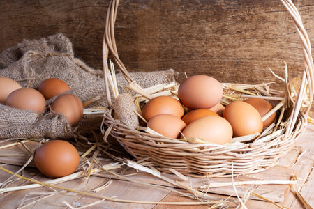 Close-up shot of fresh eggs and hen eggs with dried straw lying on wooden table in organic farm.の写真素材