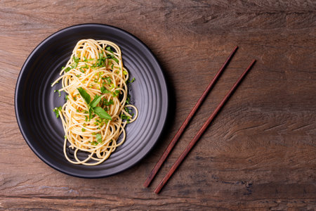 Stir-fried spaghetti or stir-fried noodles Tomato sauce and prawns on a black plate On a wooden table background. Top view.の写真素材