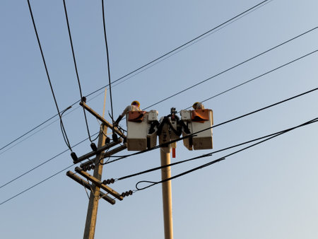 Electrician repairing cable on a power pole with electric repair service truck Internet phone back to normal.の写真素材