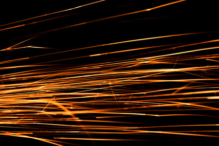 Yellow sparks from cutting metal illuminated on black background magical technology shedの写真素材