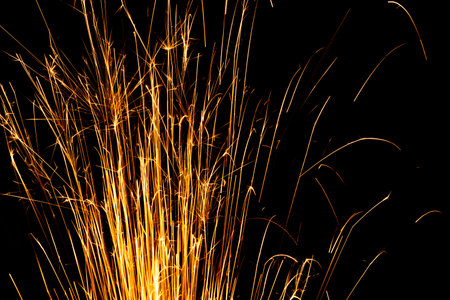 Yellow sparks from cutting metal illuminated on black background magical technology shedの写真素材