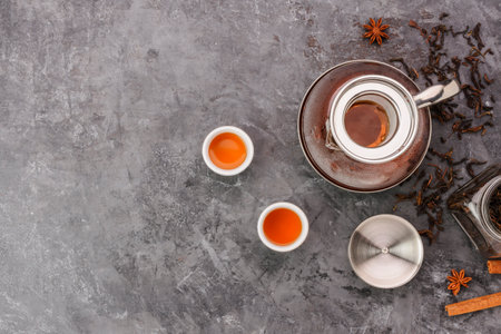 Top view of hot tea in a jug and in a teacup placed on a vintage table.