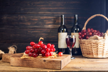 Red grapes with a bunch of grapes in a sweet natural fruit wooden basket with a wine bottle Placed...