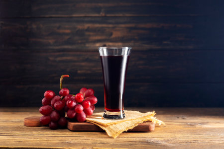 red grape juice in a glass placed on a wooden table or red wine, a delicious natural fruit juice drinkの写真素材