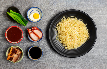 Noodles and pork soup with pork, barbecue eggs, crispy pork, dumplings, green vegetables with seasonings, healthy food, Thai, Chinese, Hong Kong, arranged on the table, top view.の写真素材