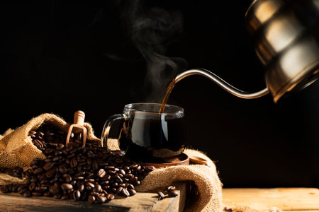 Pour black coffee into a coffee cup There are roasted coffee beans on the table. with a black background and dark colorsの写真素材
