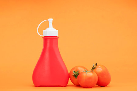 Chili sauce, plastic sauce bottle isolated on yellow backgroundの写真素材