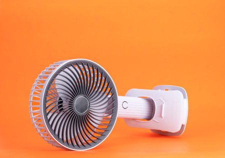 Electric fan powered by usb battery. Modern technology product design. Isolated on orange background.の写真素材