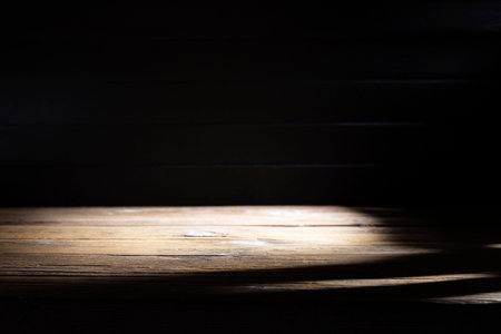 Old brown wooden floor or empty table with light coming from behind on a black and dark background.