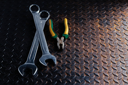 Silver wrench and pliers on rusty iron floor, top view.の写真素材