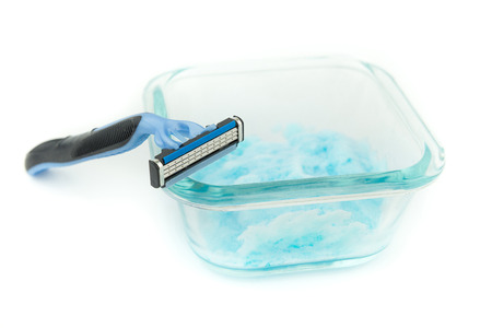 Triple razor blades for men shaving on clear glass container and  blue shaving gel, foam, isolate backgroundの写真素材