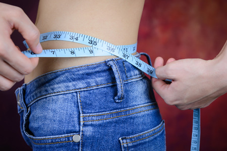 slim asian woman , wearing jeans, measuring her body shape, waist, buttocksの写真素材