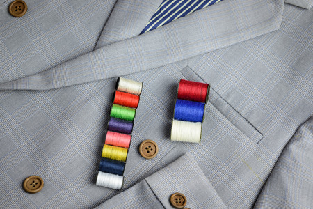 small coil of colorful thread stacking on grey suit, plaid texture