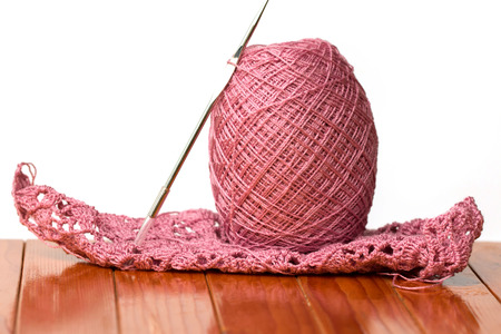 Pink yarn and needles on a chair in isolated background.