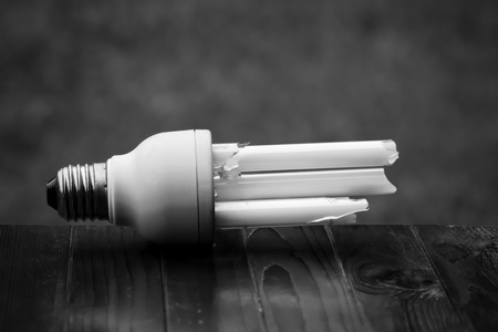 Defective bulb placed on a white and black chair. Green background And pose a danger to global warming.の写真素材