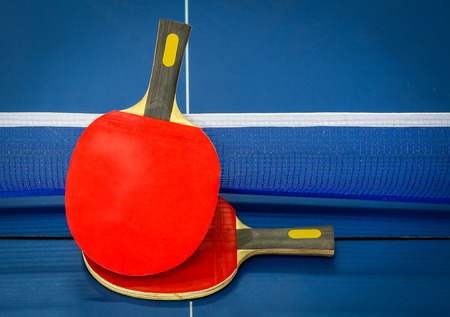 Ping-pong rackets and ball, ping pong tables blue. As in athletics.の写真素材