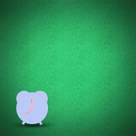 Clock by cork board on green grass backgroundの写真素材