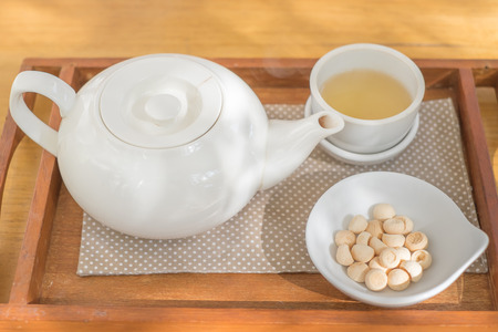 Tea cup pot with sweetmeat on the wooden plateの写真素材