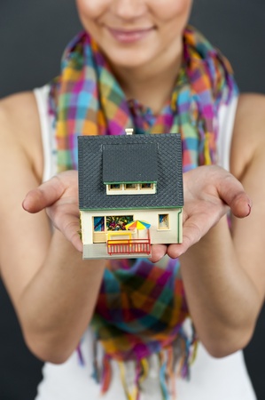woman with miniature house on black backgroundの写真素材