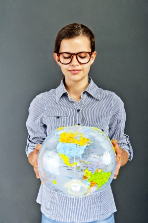 Teenager girl with blue shirt with globe ball on black backgroundの写真素材