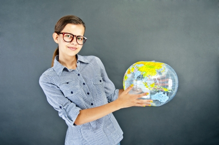Teenager girl with blue shirt with globe ball on black backgroundの写真素材