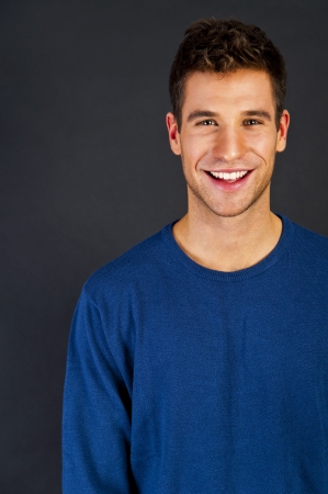 Man in blue sweter standing against the black backgroundの写真素材