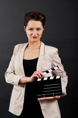 Woman with movie clap over black backgroundの写真素材