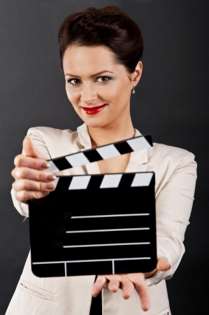 Woman with movie clap over black backgroundの写真素材
