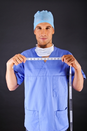 Surgeon with centimeter over dark backgroundの写真素材