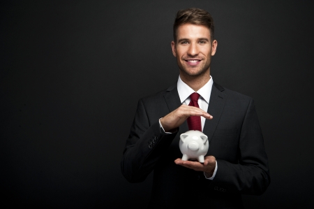 Businessman with piggy bank over dark backgroundの写真素材